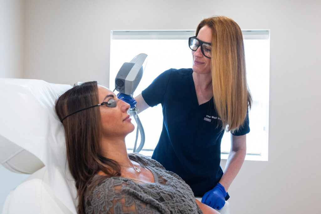 A technician is holding up a handheld device up to a patient's face for Intense Pulsed Light near Cleveland.