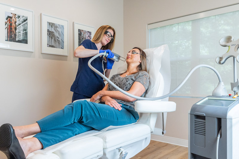A patient lies down and a provider applies laser energy to her skin for laser skin resurfacing in Westlake.