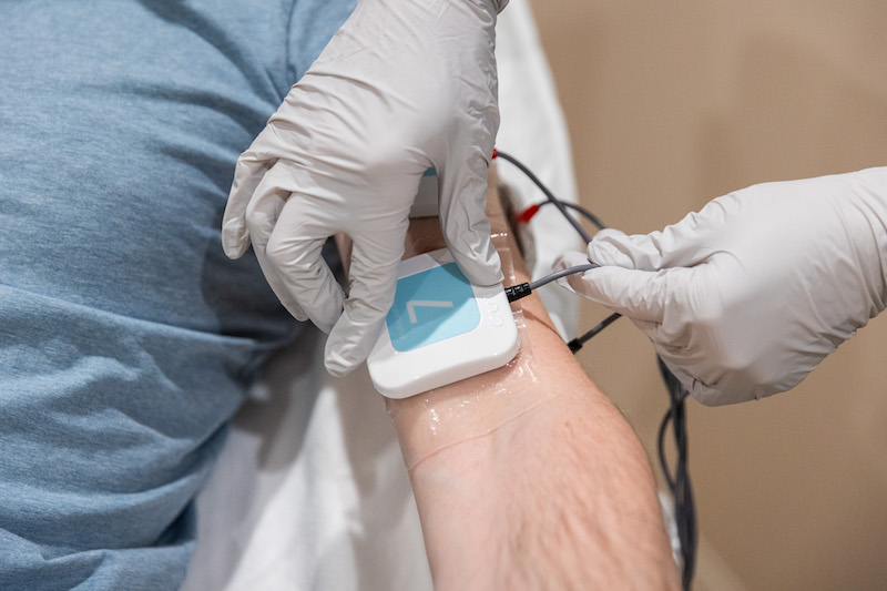 A man is lying down with electrodes attached to his arm for TruFlex near Cleveland.