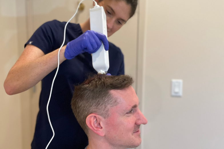 A provider from our team of holistic doctors in Cleveland administers a patient's hair restoration therapy.